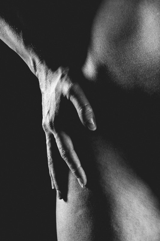 Käsi alastomalla lantiolla, mustavalkoinen kuva